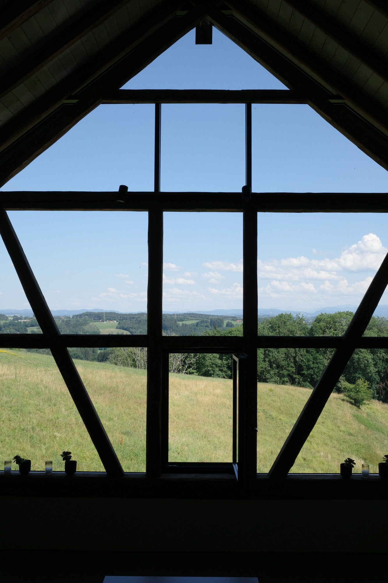Ein gro&szlig;es Fenster mit Blick &uuml;ber Wiesen und W&auml;lder.