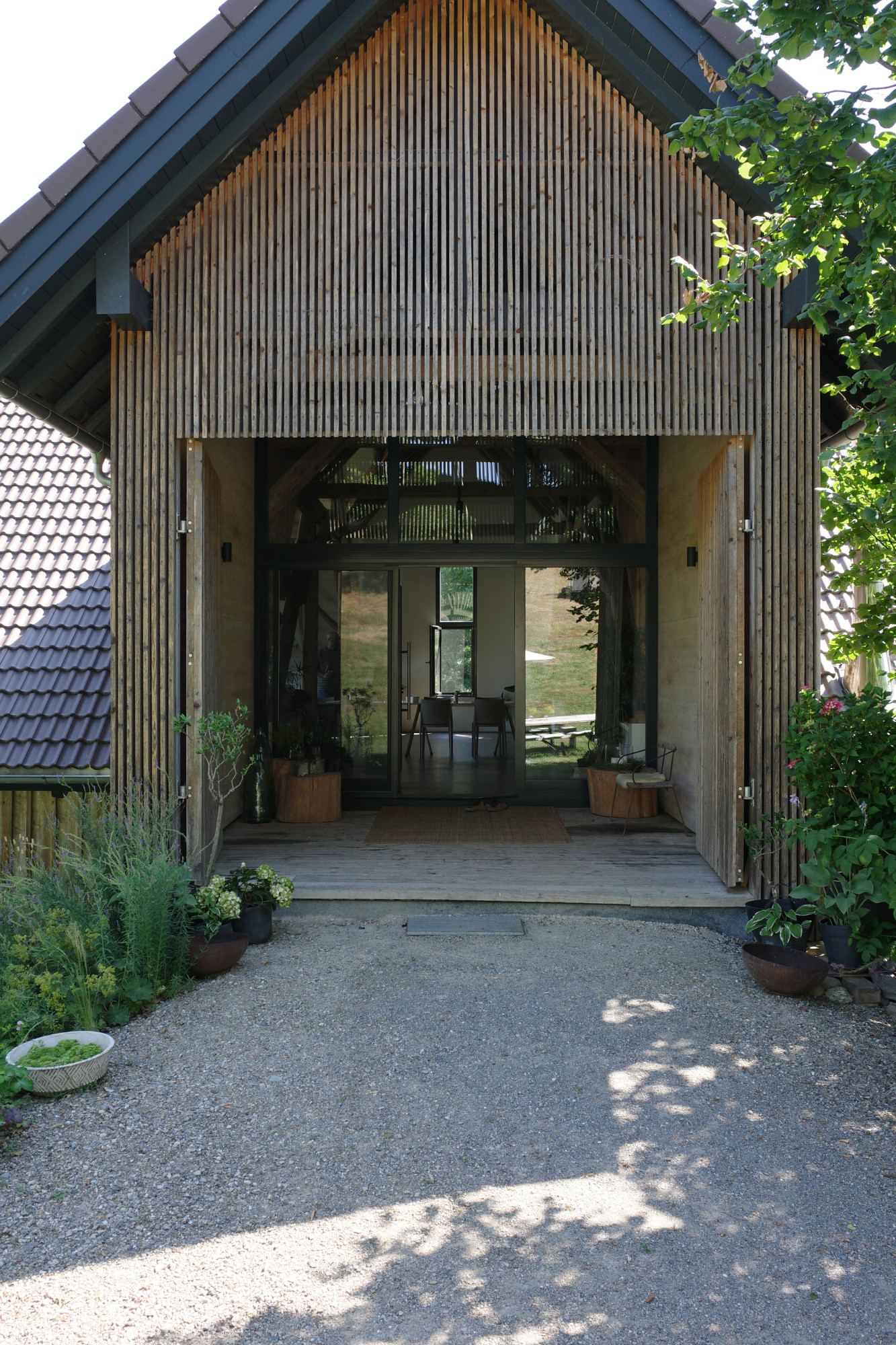 Eingang eines Hauses mit Holzfassade und gro&szlig;er Glasfront.